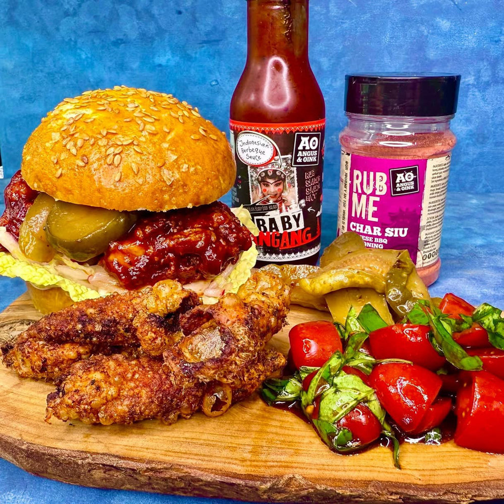 Plated meal with burger, chicken wings, and vegetables on a wooden board against a blue background