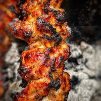 Close-up of a skewer with grilled meat on a grill