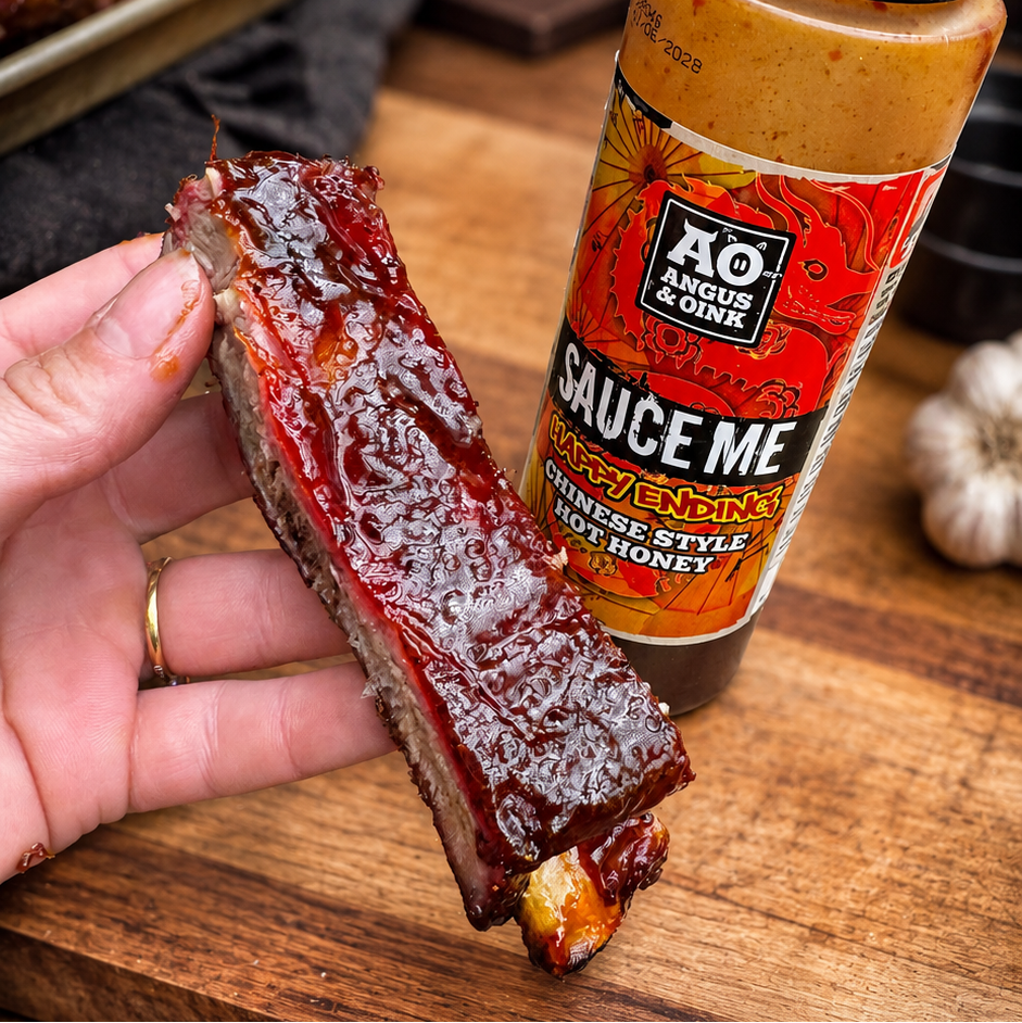 Sliced meat with a bottle of sauce on a wooden cutting board
